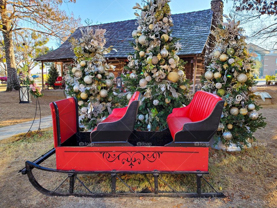 Santa's sled sits in front of beautifully decorated Christmas trees