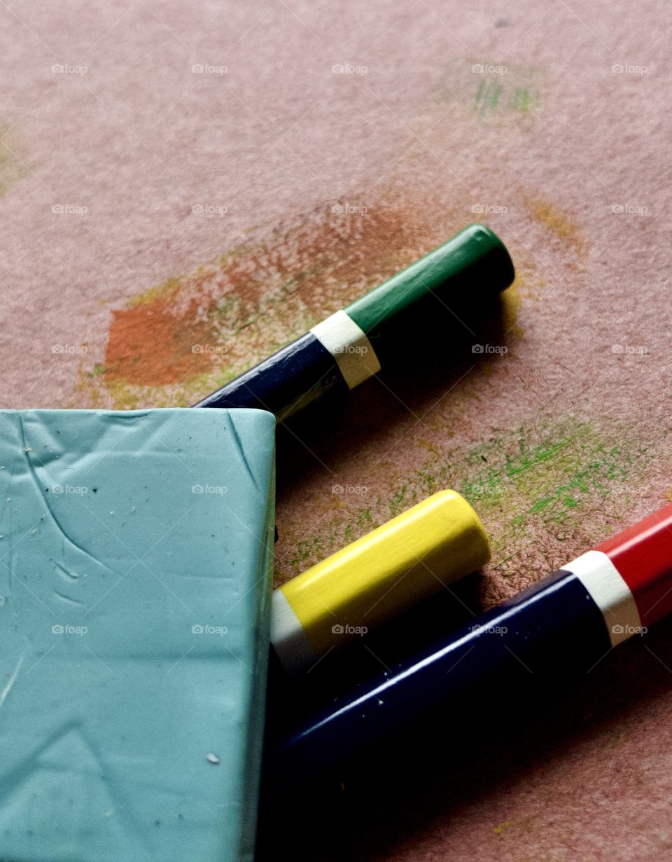 Macro overhead view of blue eraser and red green and yellow pencils 