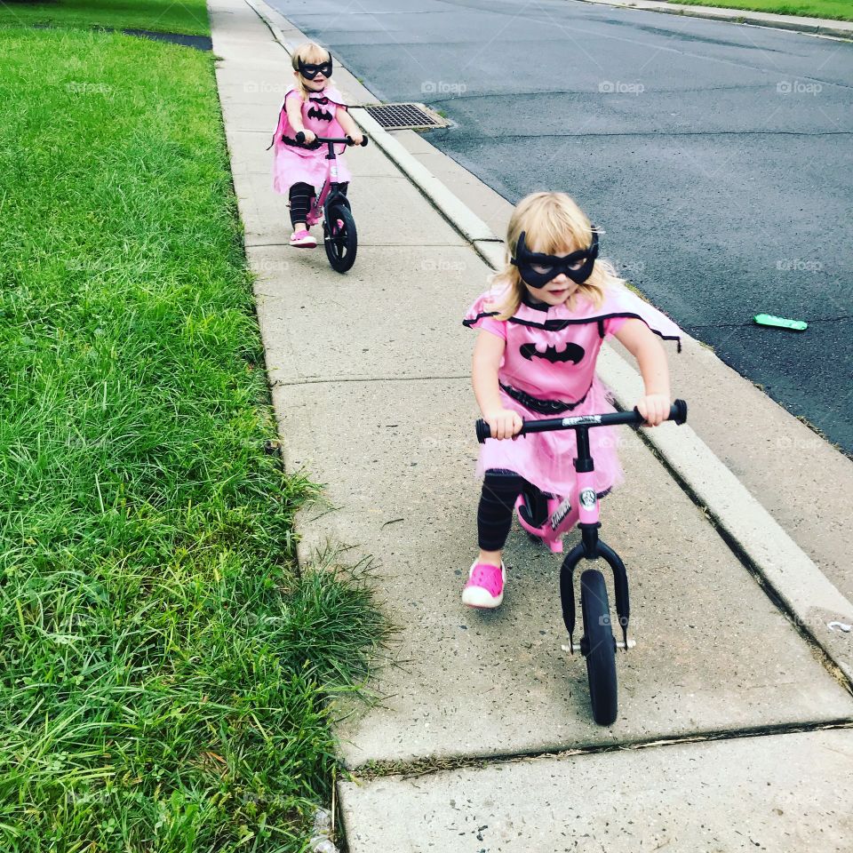 Twins riding bike as bat girls. 