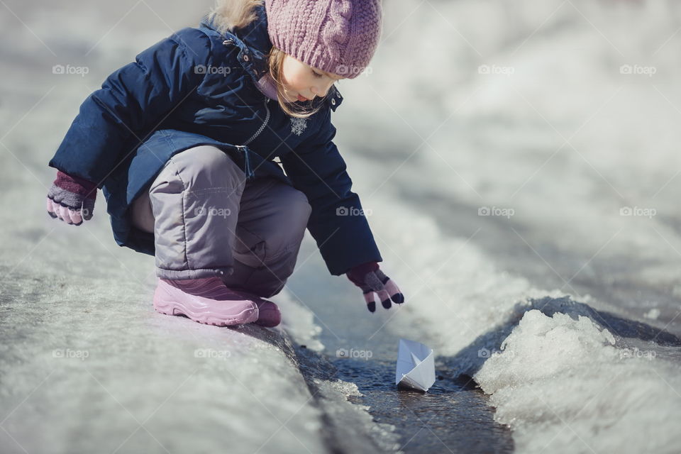 Little girl with paper boat on creek 