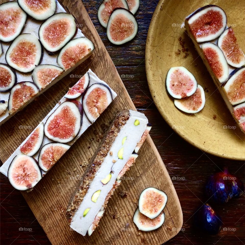 Cashew fig bars sliced on a wooden cutting board and a plate.