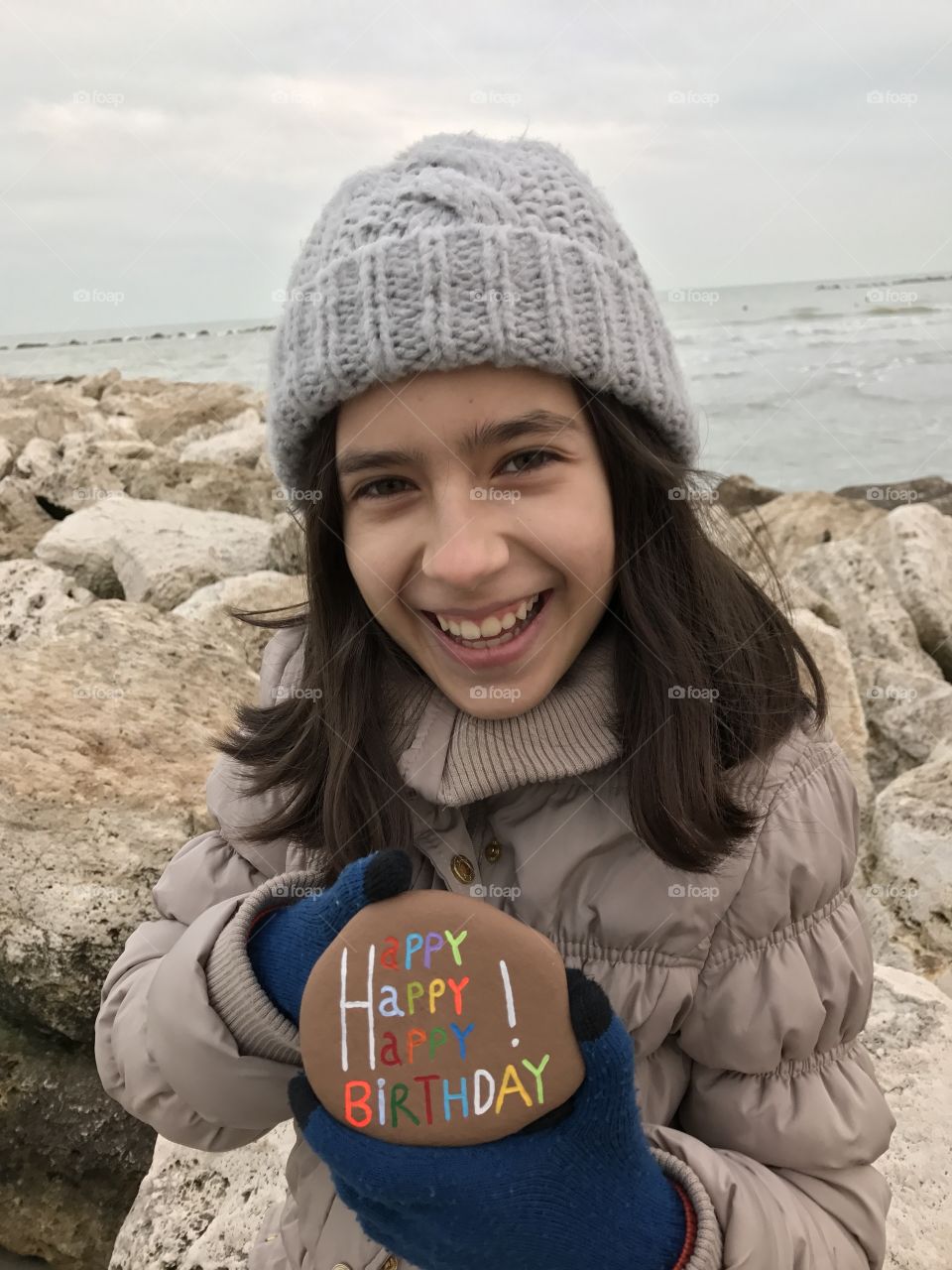 Girl holding pebble stone with birthday text at beach