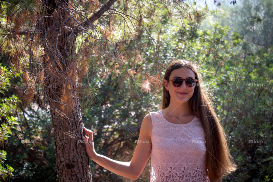beautiful girl in pink dress poses near a tree