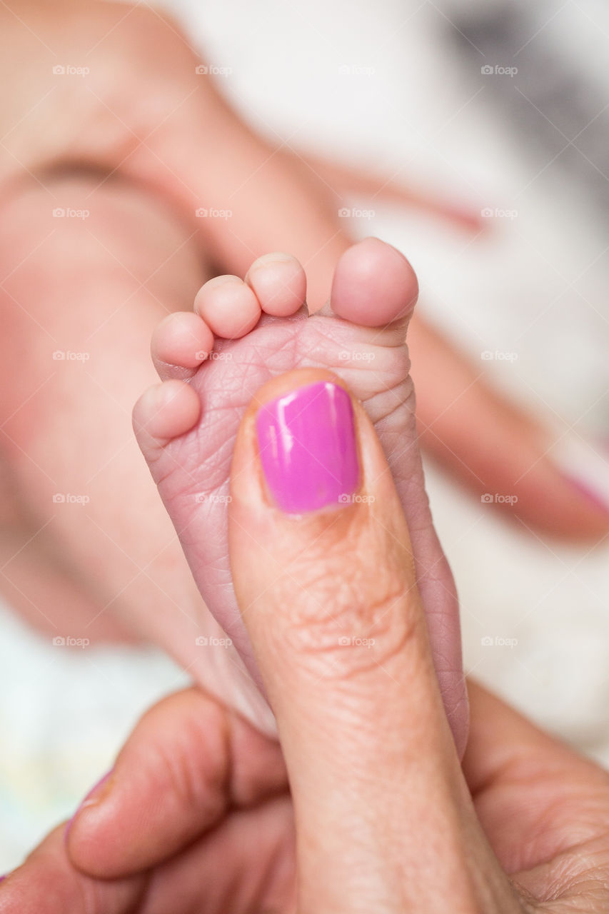Summer memories of having a new baby in the house. Image of newborn foot and mom's thumb
