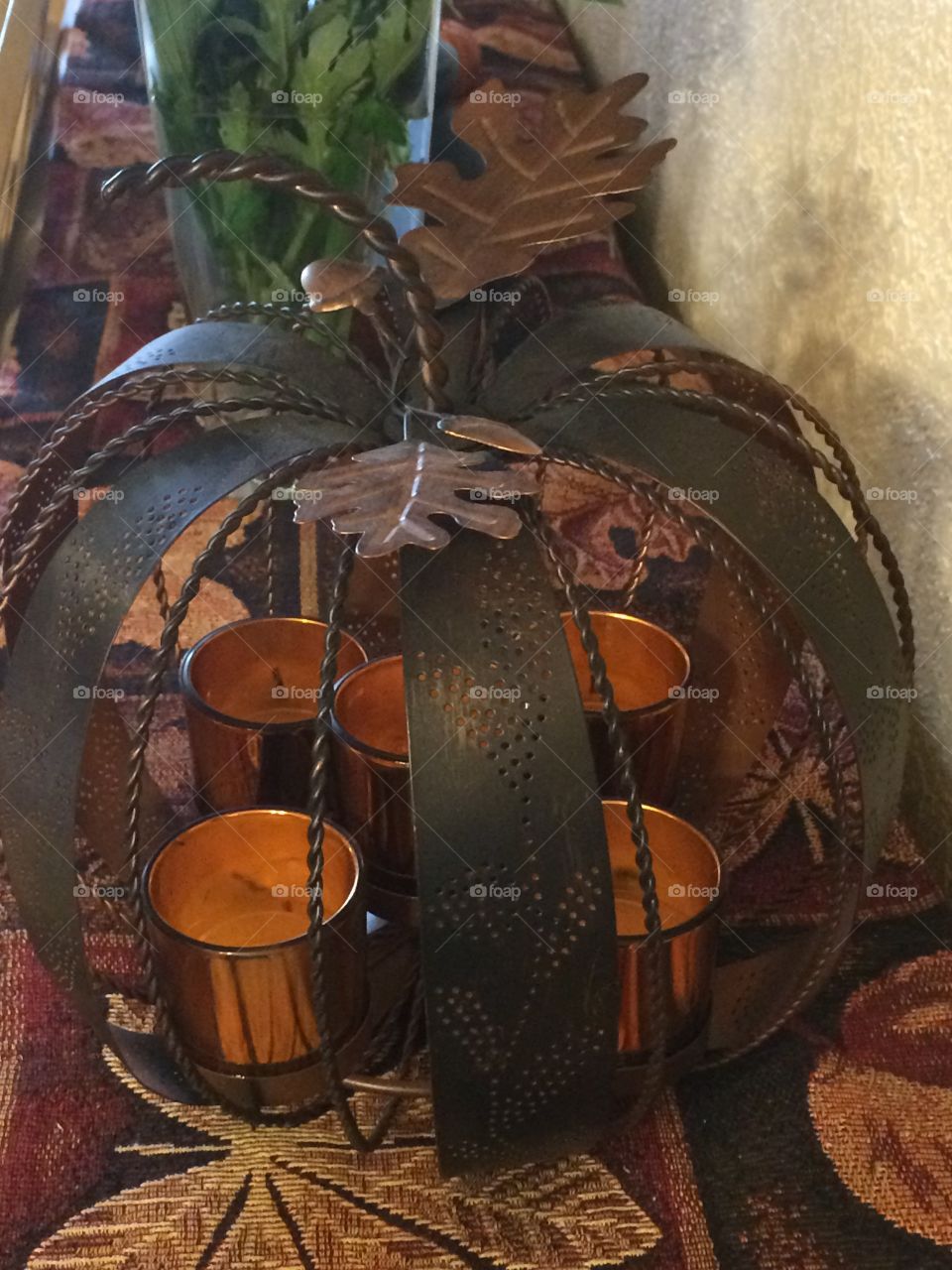 A pumpkin tea light holder with leaf motifs and orange color theme. Taken in low light. 