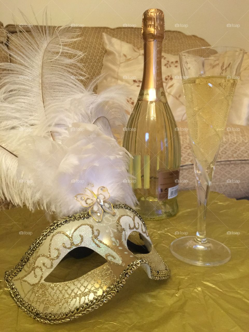 Gold Venetian masquerade mask with a bottle of Moscato And a glass of white grape juice 