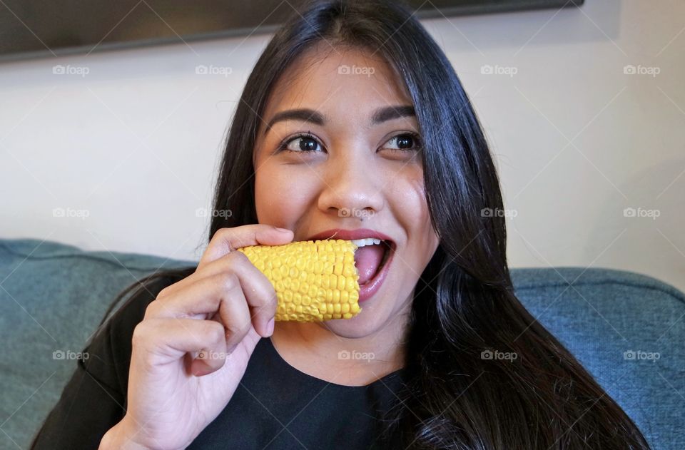 Young asian woman eating corn