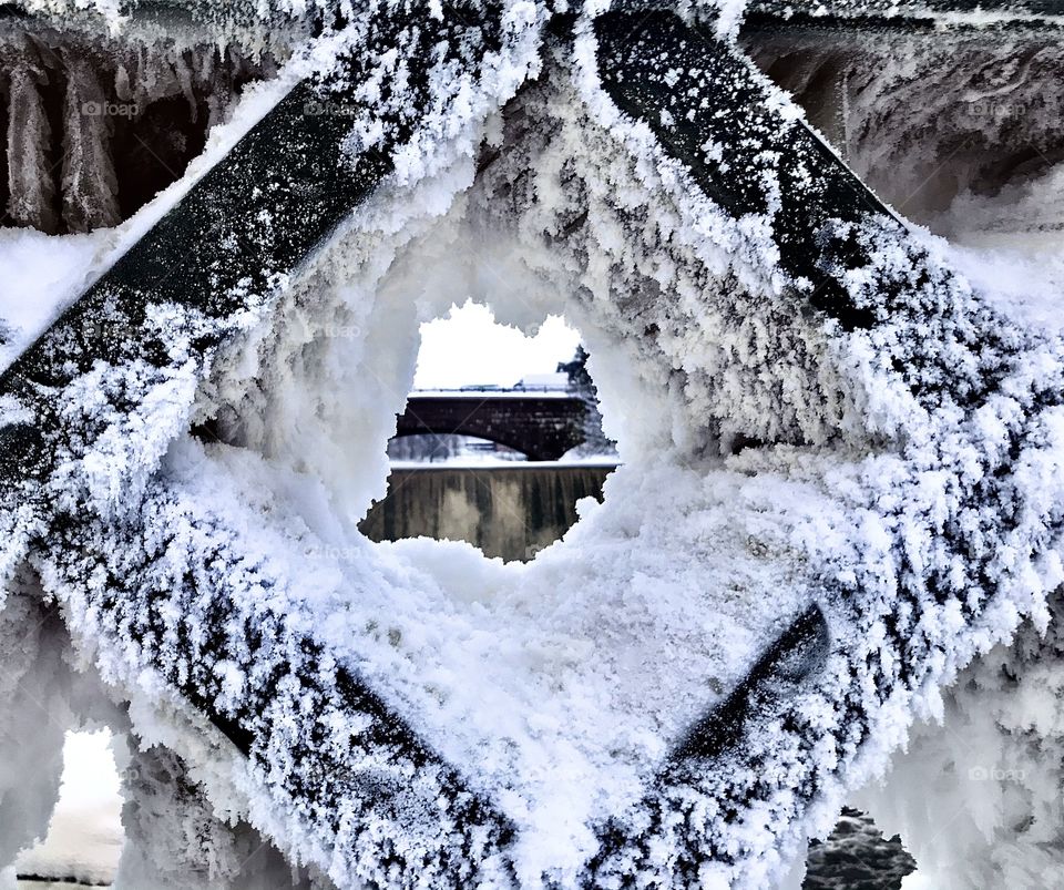 Peak at Vantaankoski rapids from frozen hole in fence, Old town Helsinki, Finland