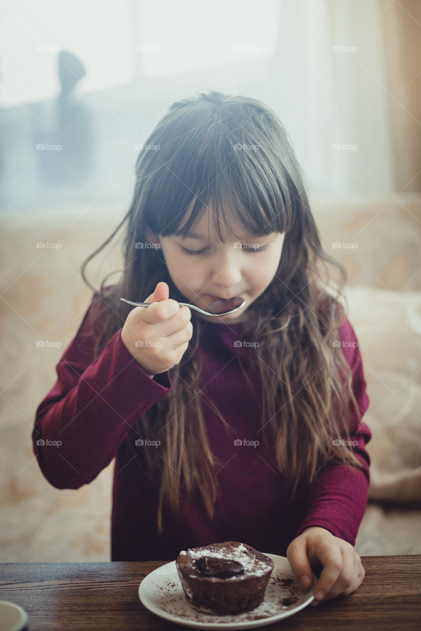 Little girl eating the chocolate muffin