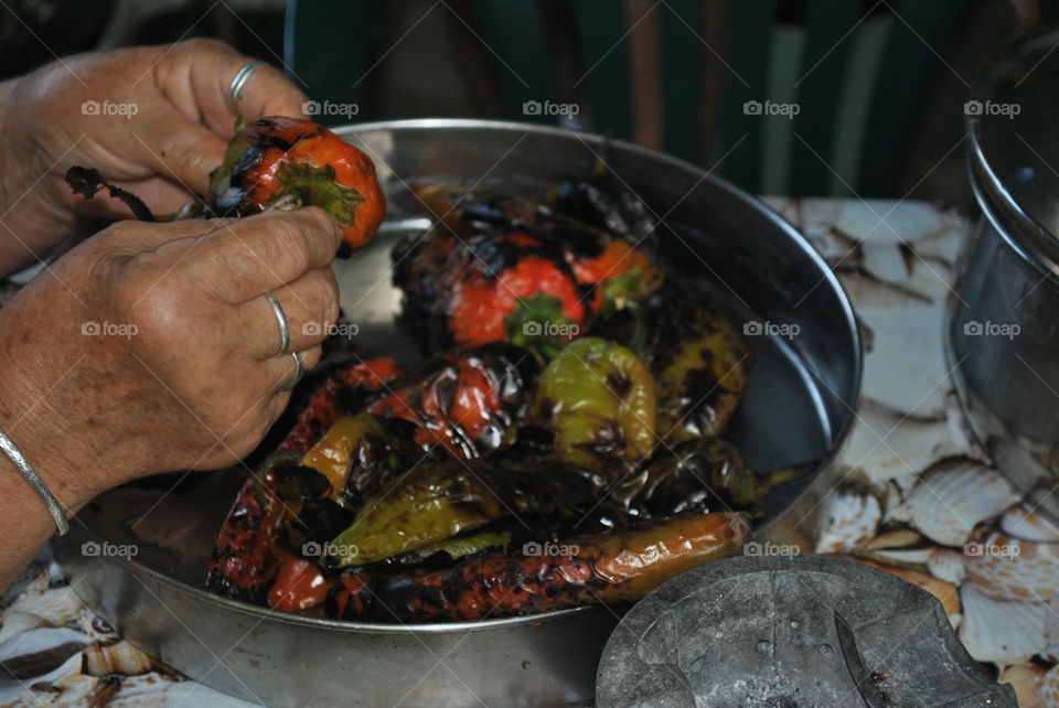 My grandmother peeling grilled peppers at home