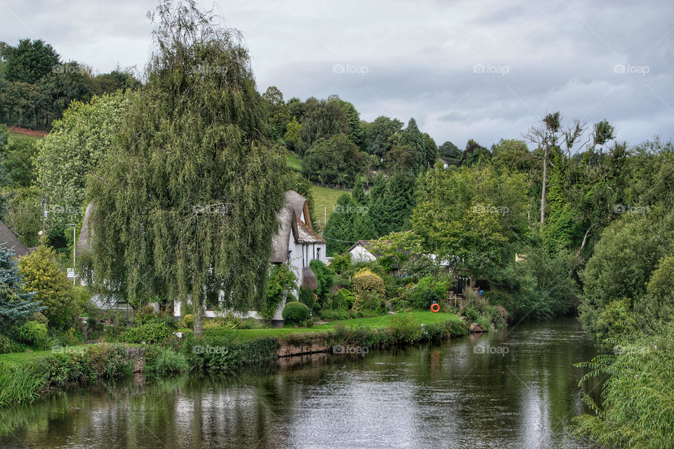 scenic view of a thatched cottage on a riverbank