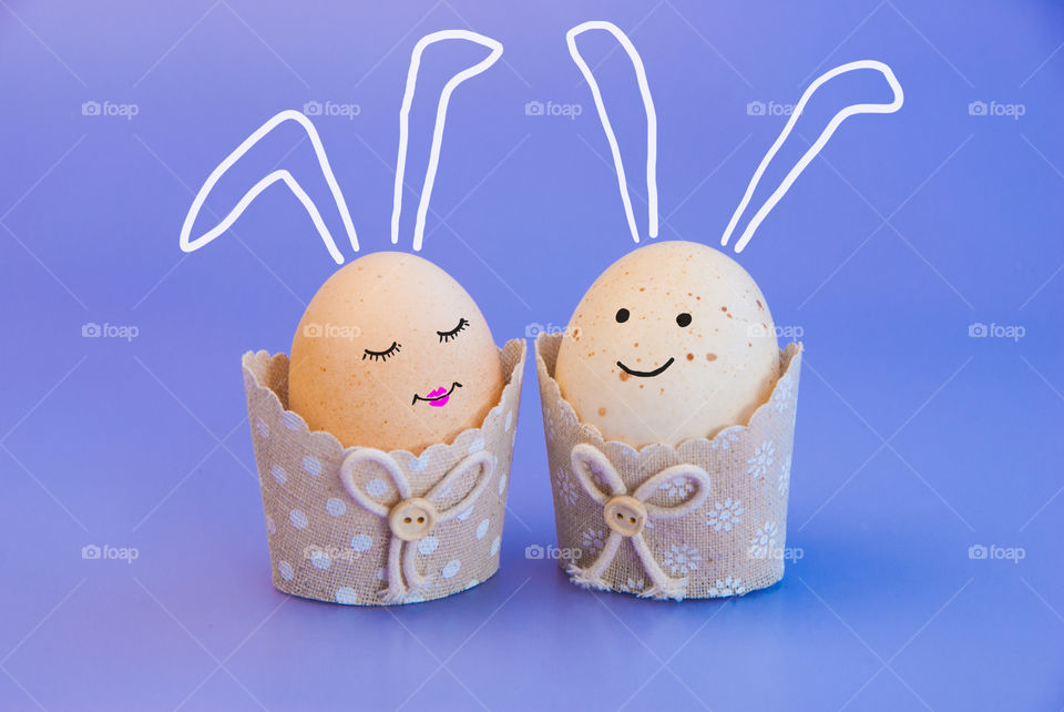two eggs in textile cups with drawing faces and ears