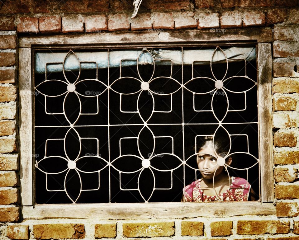 Indian girl gazes through window, India, Maharashtra. Indian girl gazes through window, India, Maharashtra