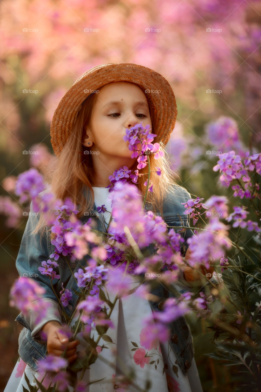 Cute little girl portrait in blossom meadow at sunset 