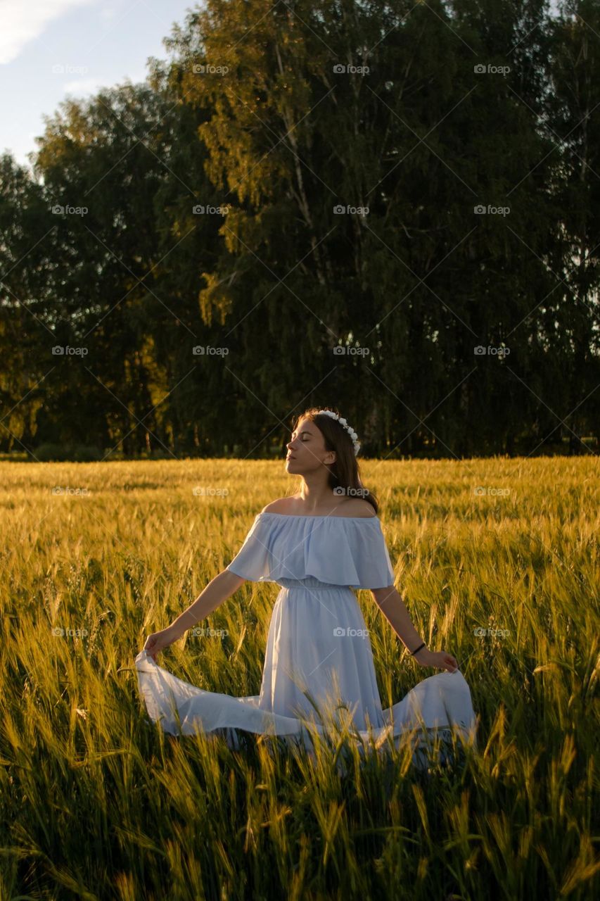 Young woman in the meadow enjoying the sunset 