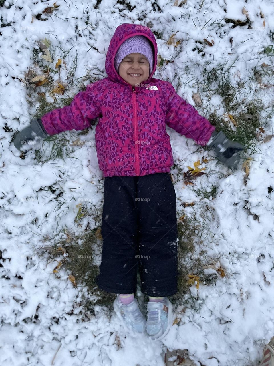 First snow angel of the year, little girl makes a snow angel in the backyard, little girl loves winter time 