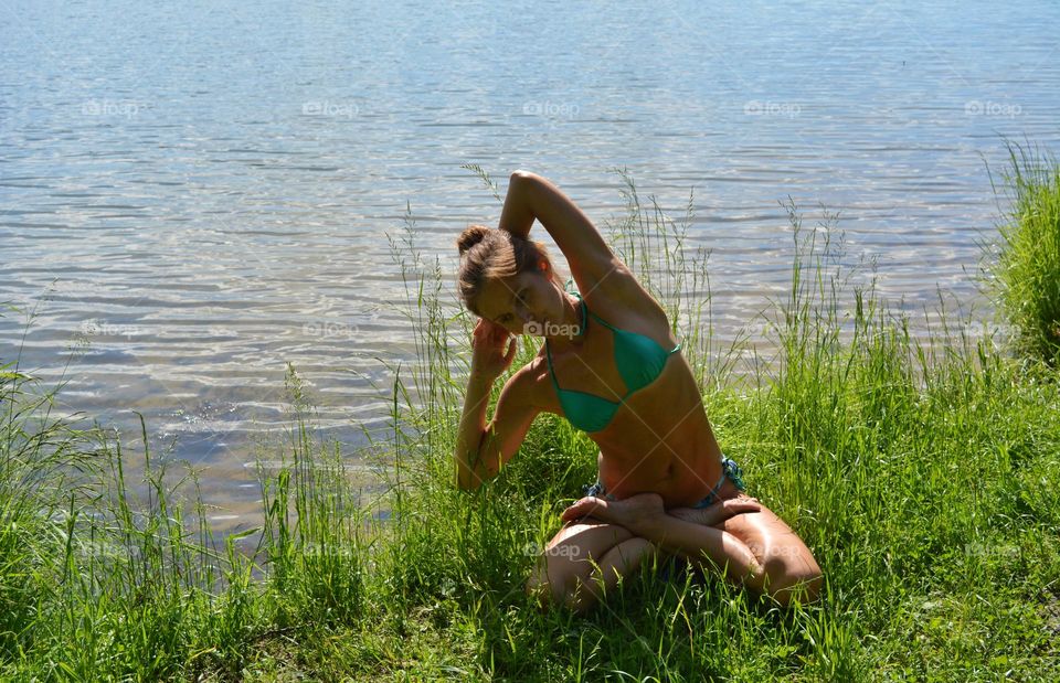 woman training yoga on a lake shore summer time