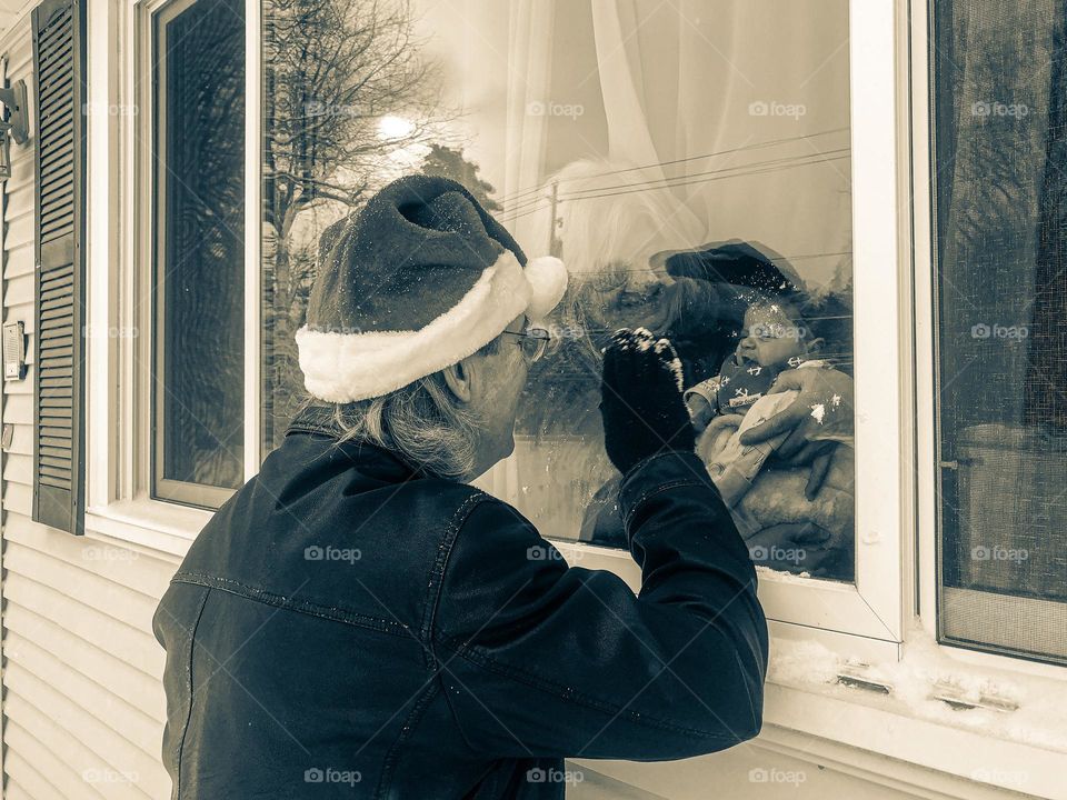 Grandfather playing Santa, playing Santa for baby, grandchild sees Santa for the first time, monochrome photo of grandparents showing baby Santa Claus 