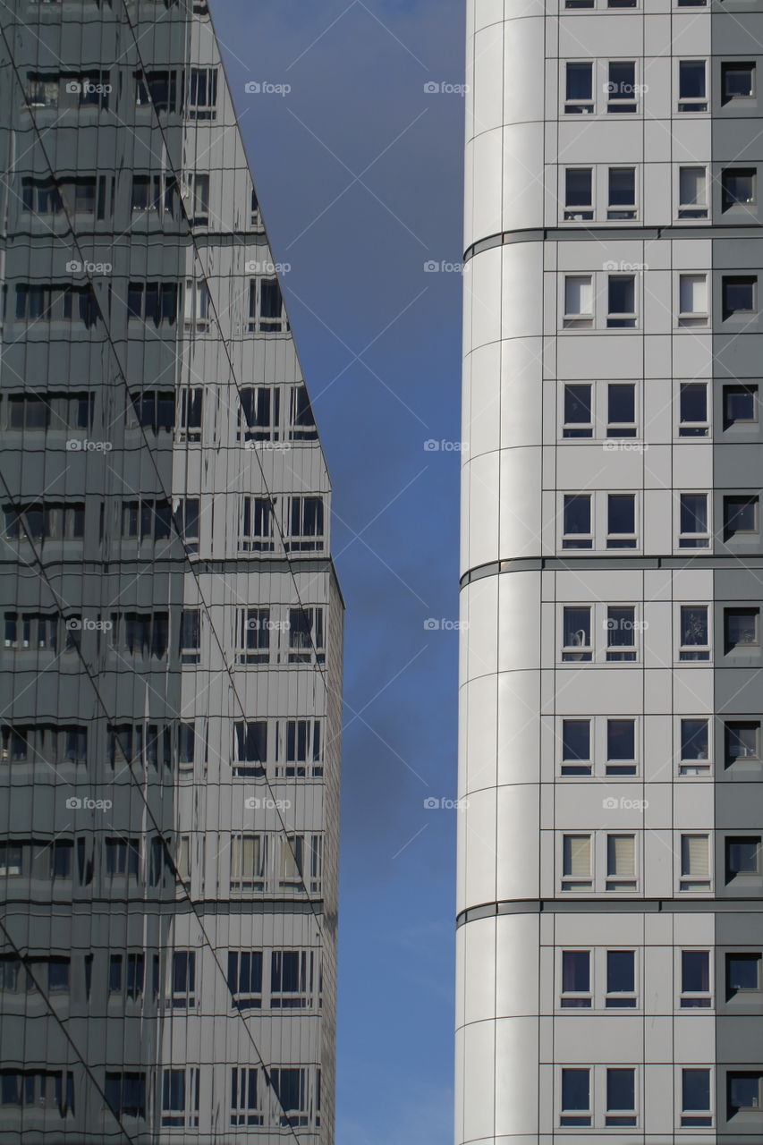 A tall skyscraper reflected in the glass fronted windows of another in a city or urban environment,
