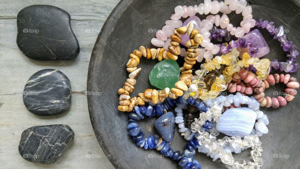 Gem stones in a black bowl on a rustic  grey wooden background with zen stones