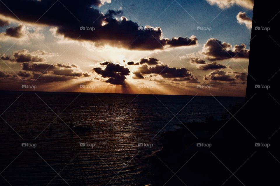 Brilliant sunset on the beach of Cancun Mexico with backlit clouds and vivid sun rays. 