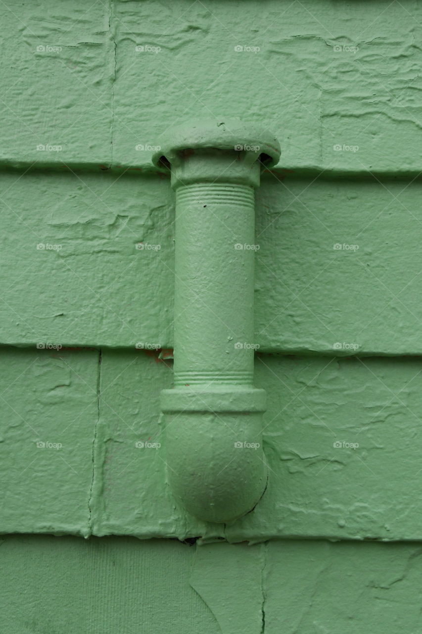 green pipe on green siding