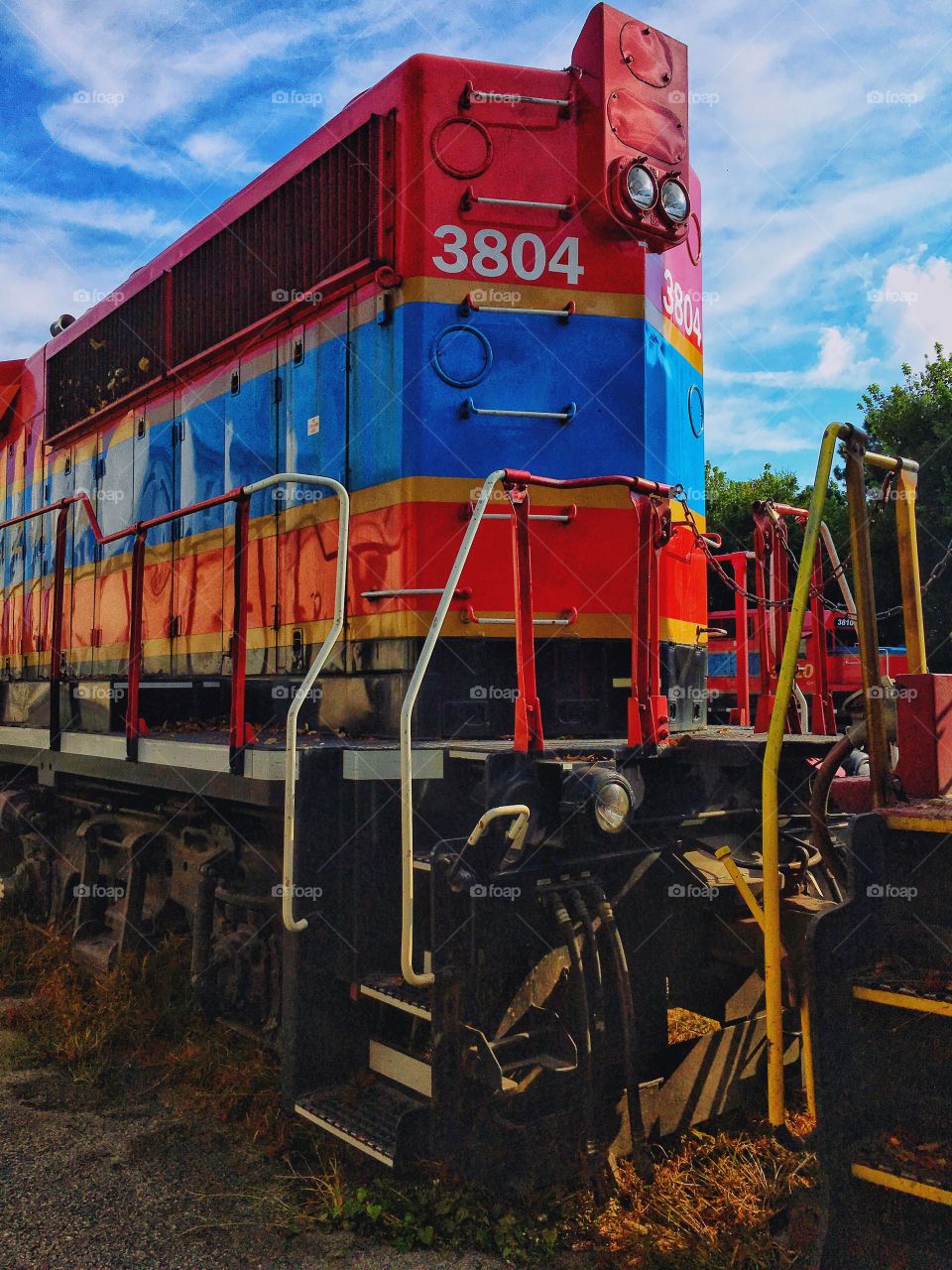 Red and blue train engine on a bright afternoon.