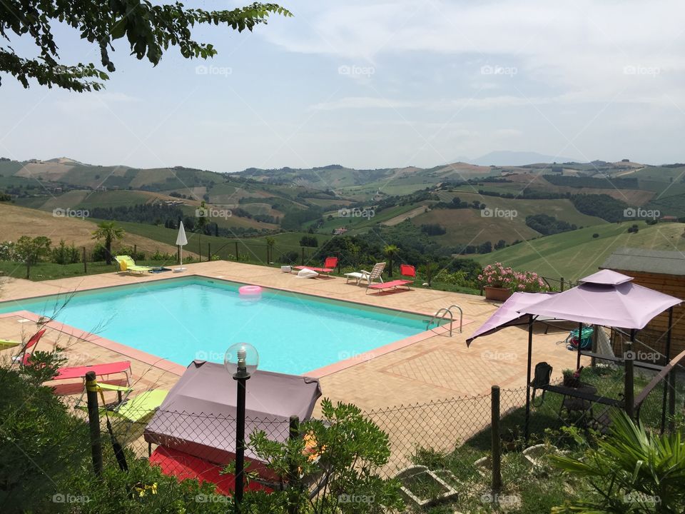 Swimming pool view with hilly landscape, Marche region, Italy