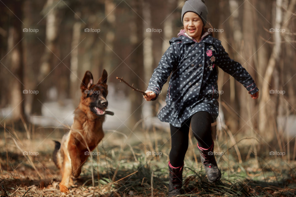 Girl walking with German shepherd puppy in a spring forest 