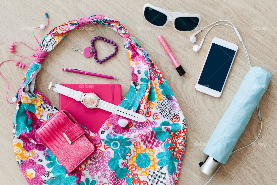 Smartphone sunglasses wallet notebook and other things pulled out of handbag put on a table