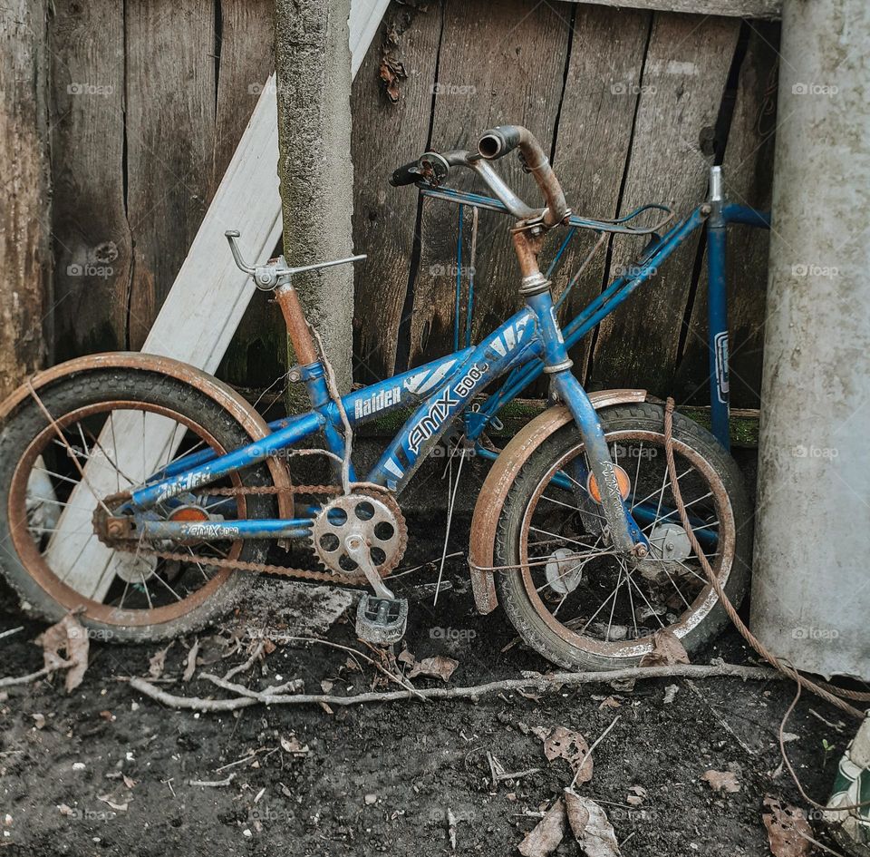 An old children's bicycle among the ruins of an old house that causes sadness