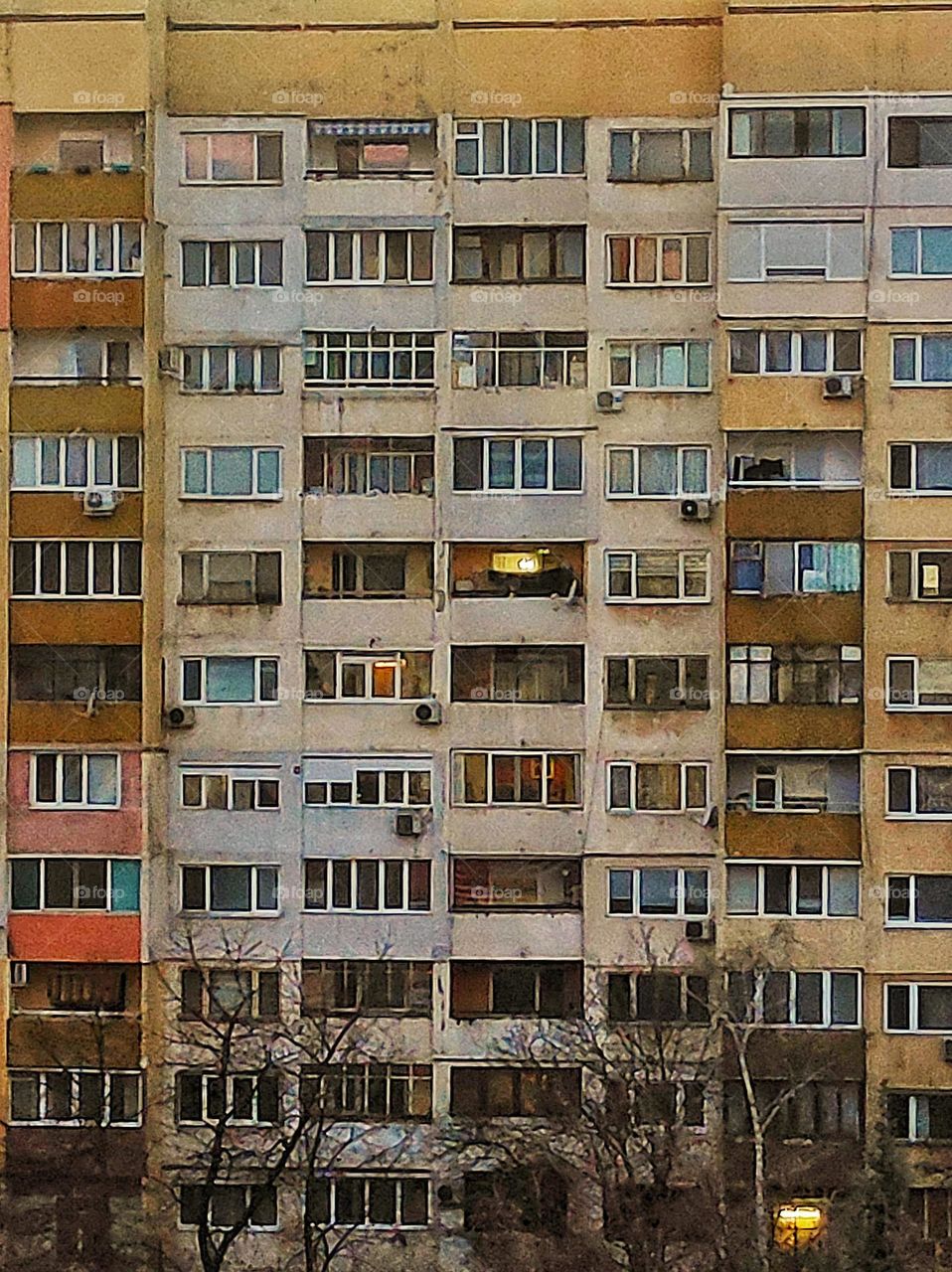 A photo of an old panel apartment building in a neighbourhood in Bulgaria with different colours and windows