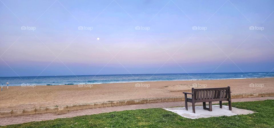 Bench with sunset, ocean, and beach view