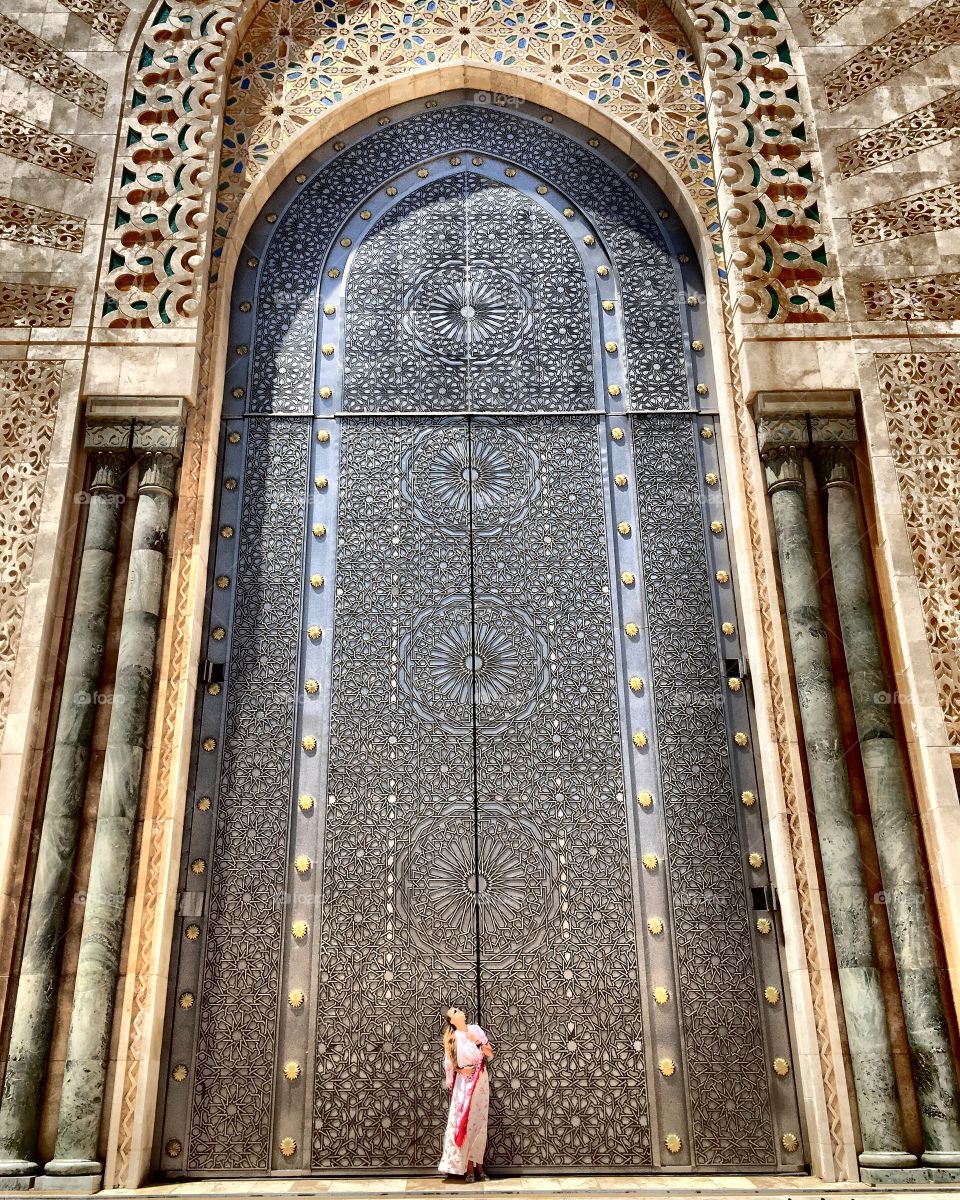 Woman standing at gate of hassan li mosque, Morocco