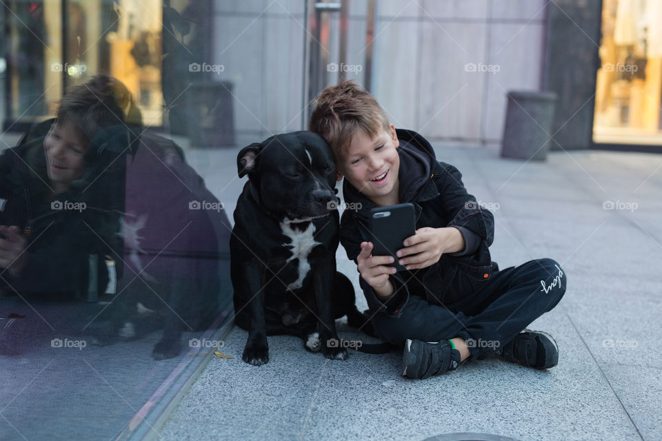 cute baby and his friend dog, sitting together on the street, and taking a selfie.  quarantine distance, empty city.  child and dog.  friends.  no one around