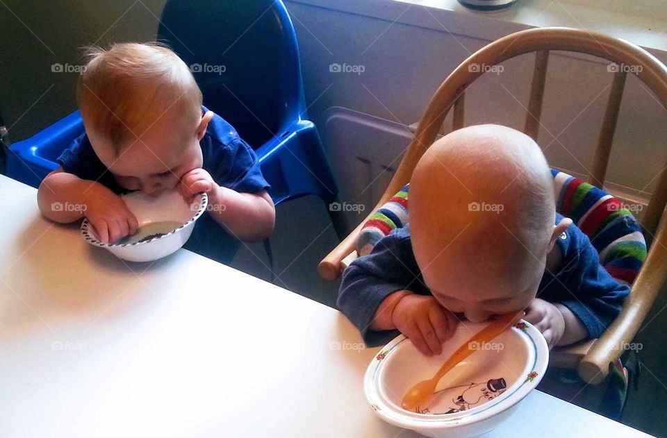 Two kids, so hungry the are eating the bowl itself.
