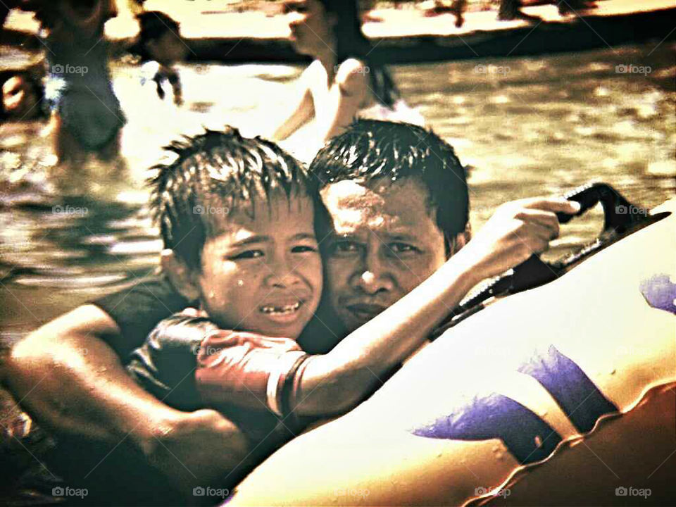 Small boy in swimming pool with his father