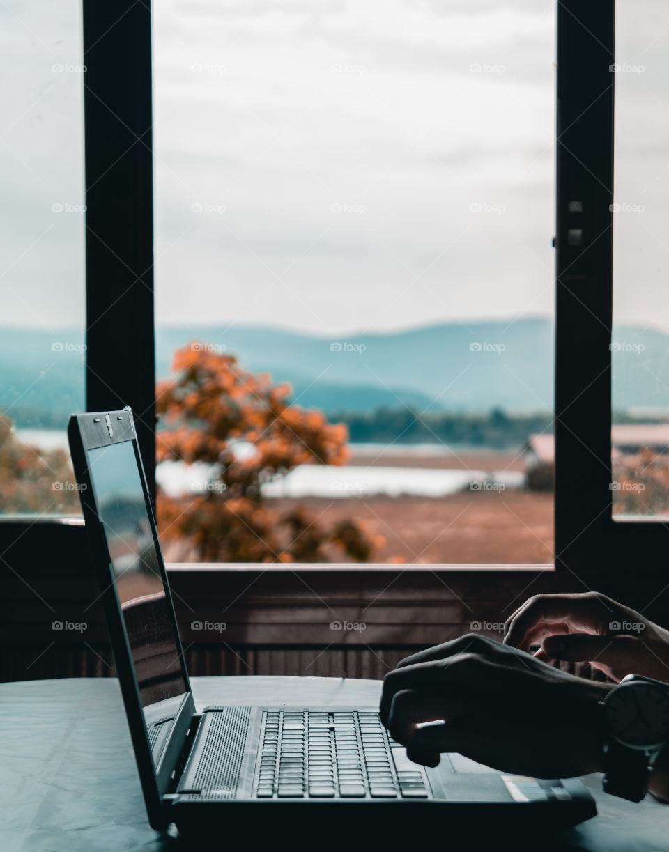 Man working on a laptop with a stunning panoramic background view.