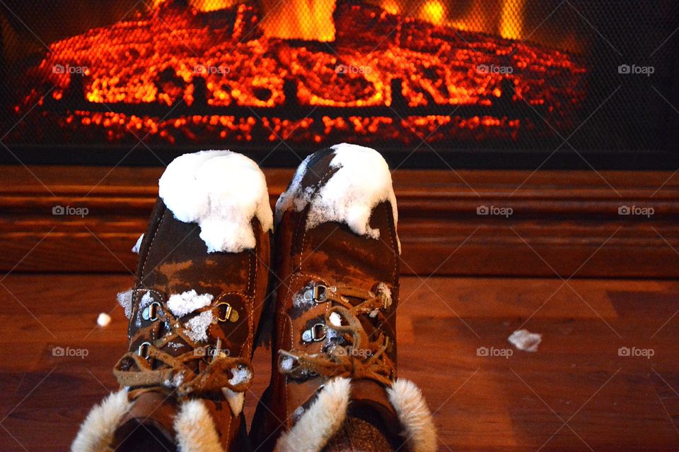 Snow covered feet / boots warning up in front of a fireplace on a cold winter day