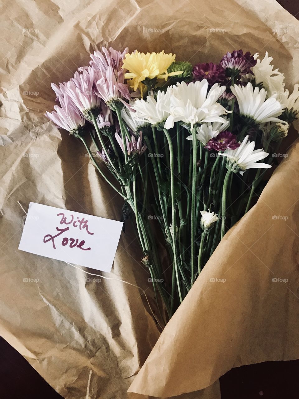 Colorful Flowers wrapped in brown paper with a written note saying with love ❤️
