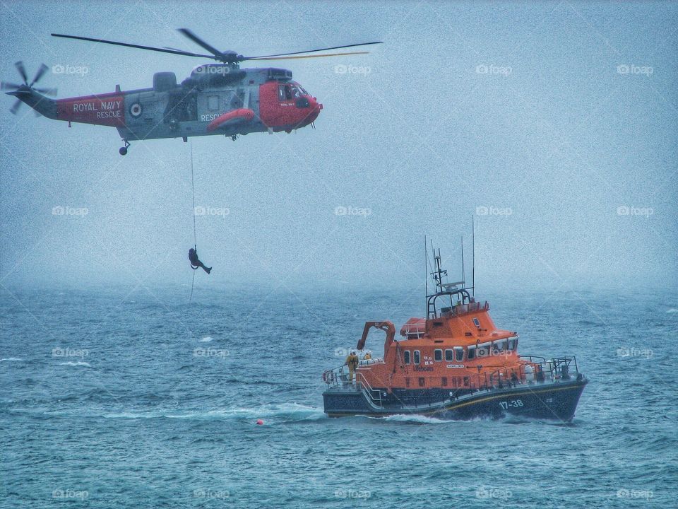 An Air and Sea Rescue taking place on a misty ocean.  Royal Navy Helicopter and RNLI lifeboat involved in a dramatic airlift.