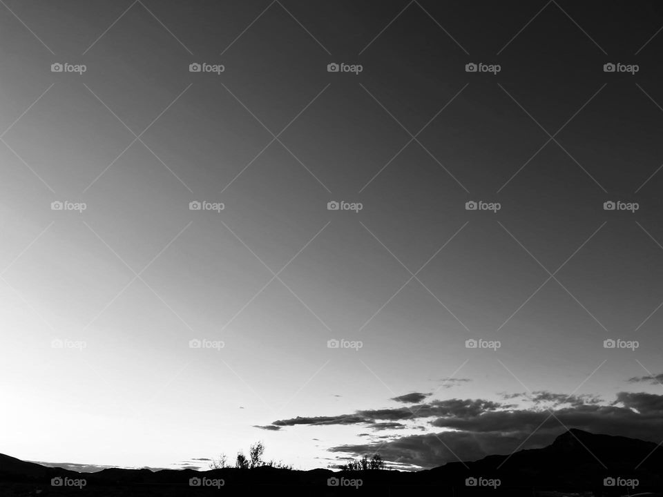 A black and white photo of a cloudy sky and a mountain. 