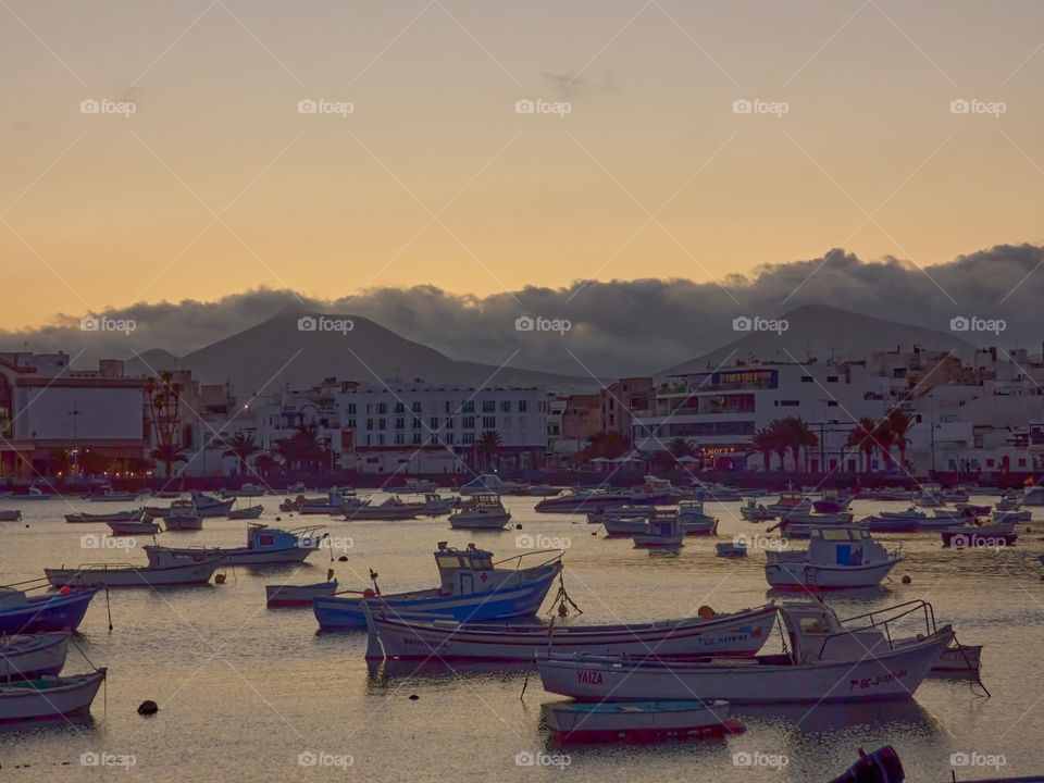 Paisaje marinero con botes de pesca y recreo con fondo de montaña y nubes al atardecer