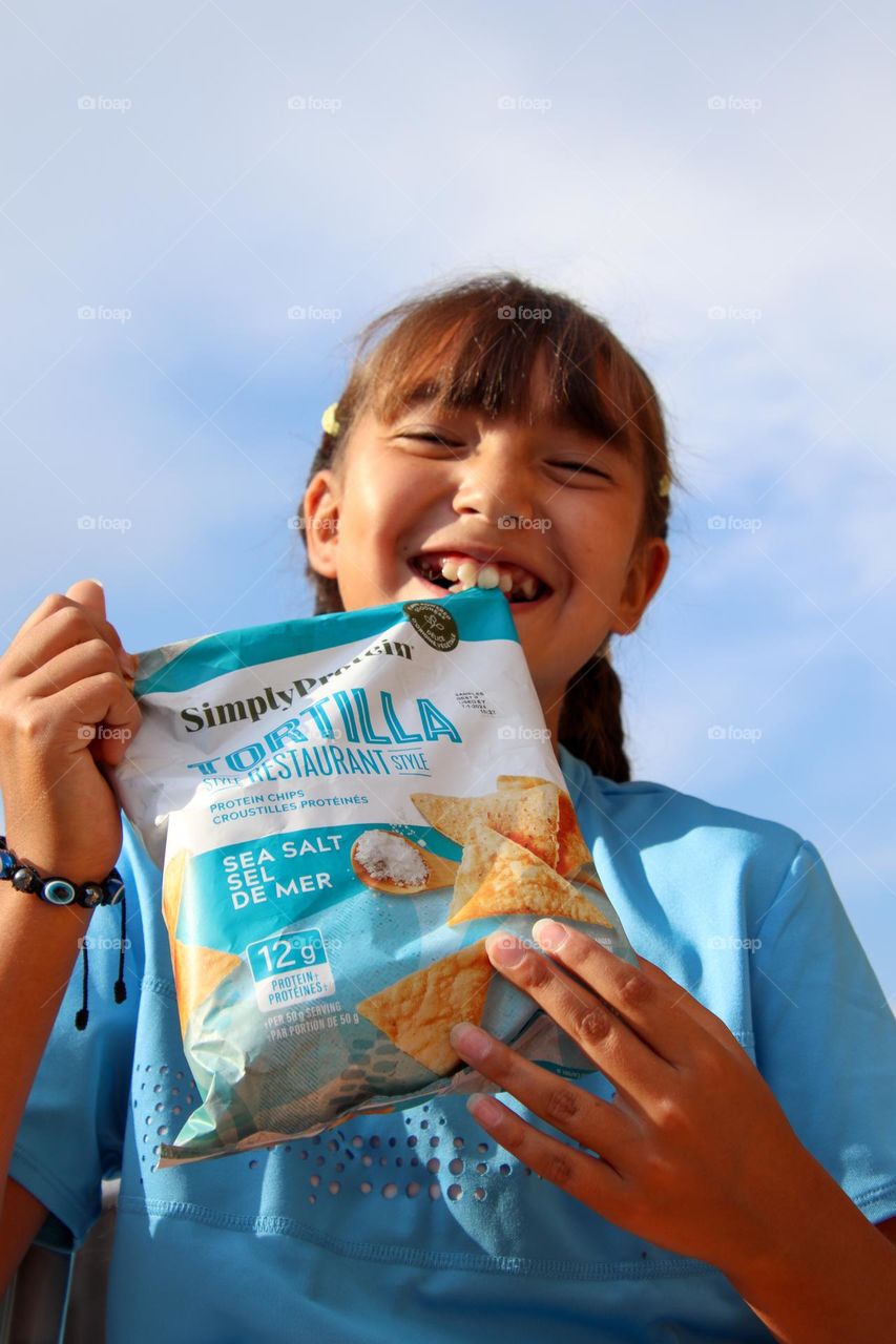 Cute happy girl with a bag of chips