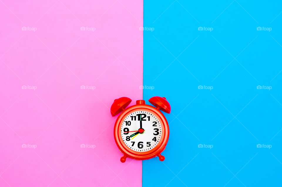 Clock isolated on pink and blue background with copy space 