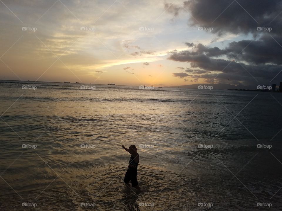 Boy plays in the ocean at waikiki beach
