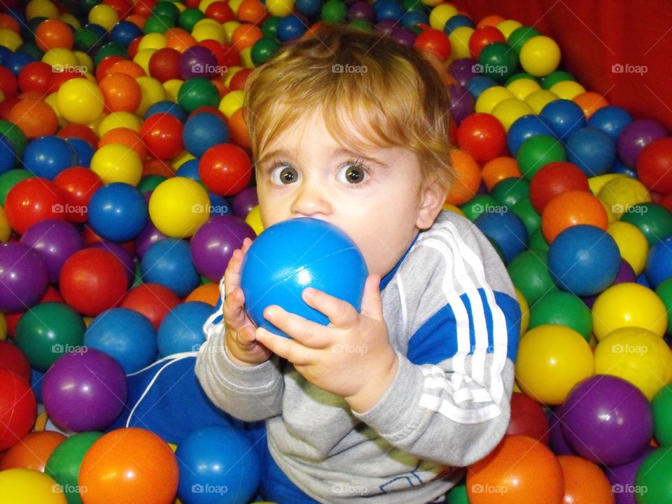 A baby playing with colorful balls at playground 