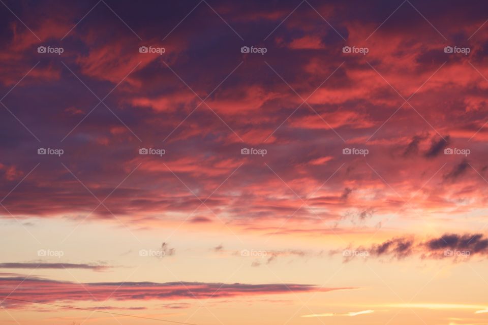 A canopy of brilliantly colored clouds in a pastel-yellow sky