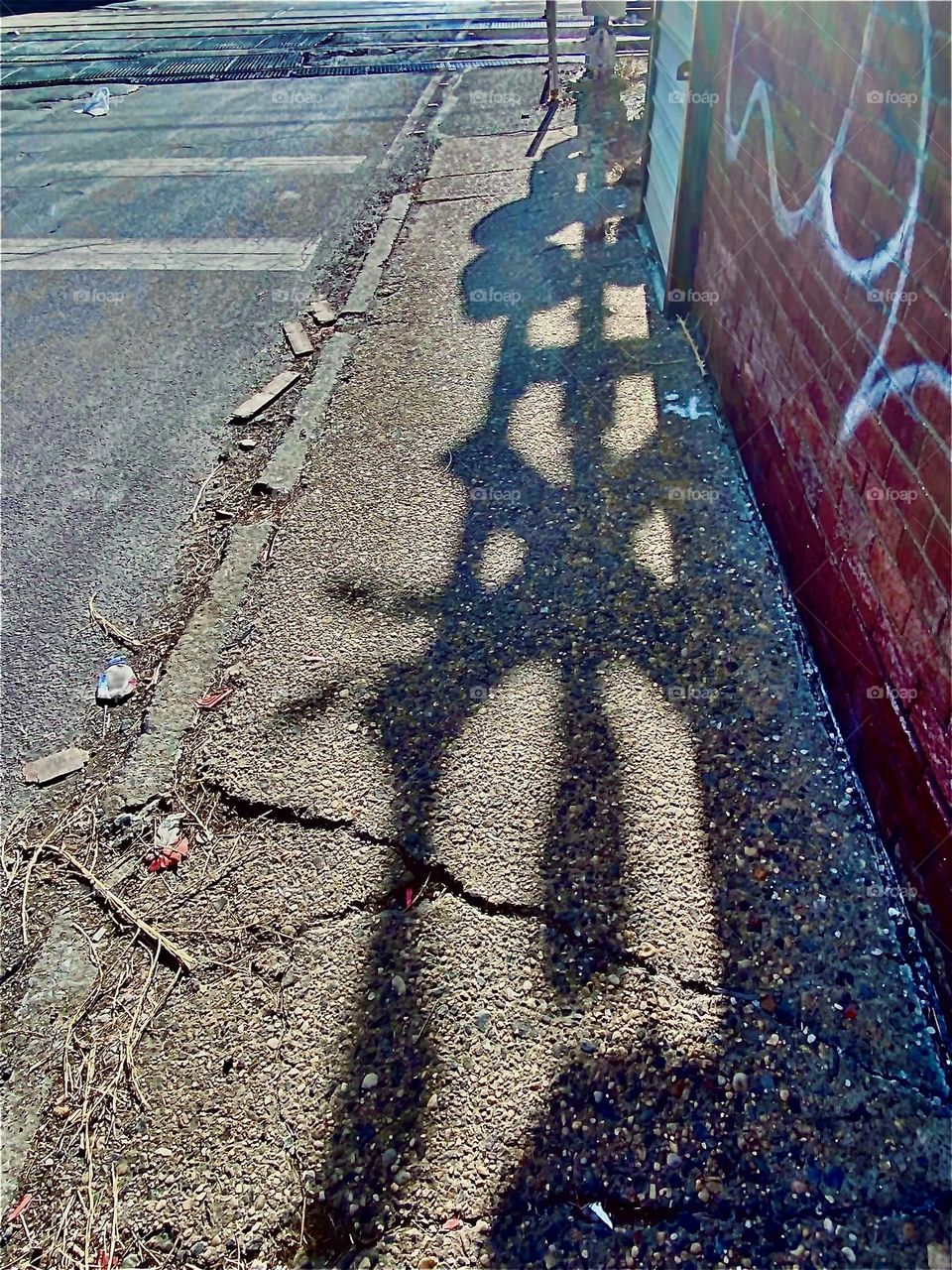 A beautifully formed shadow of the “NO CROSSING” sign in front of the train tracks beneath the Pulaski Bridge in LIC, Queens, NY. We walk through here regularly to get to our boat in the East River at Newtown Creek. 2022. Hypnotic Productions