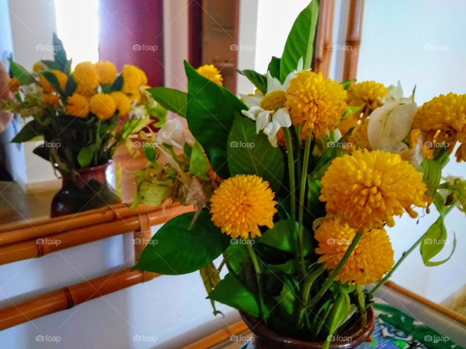 Yellow chrysanthemums and white daisies in a pottery vase